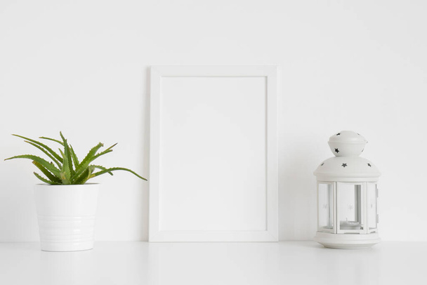 White frame mockup with a succulent plant and a candle holder on a white table. Portrait orientation. - Fotó, kép
