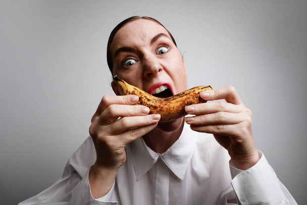 Deadline situation. Woman trying eat a ripe banana. - 写真・画像