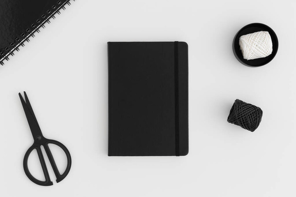Black notebook mockup with workspace accessories on a white table. - Photo, Image