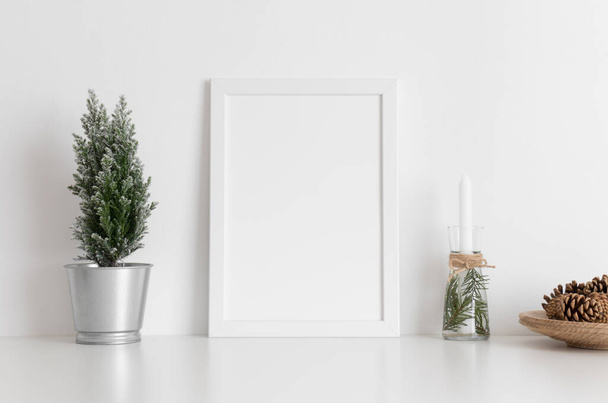 White frame mockup with a cypress tree, candles and pine cones on a white table. Christmas decoration. - Foto, Imagem