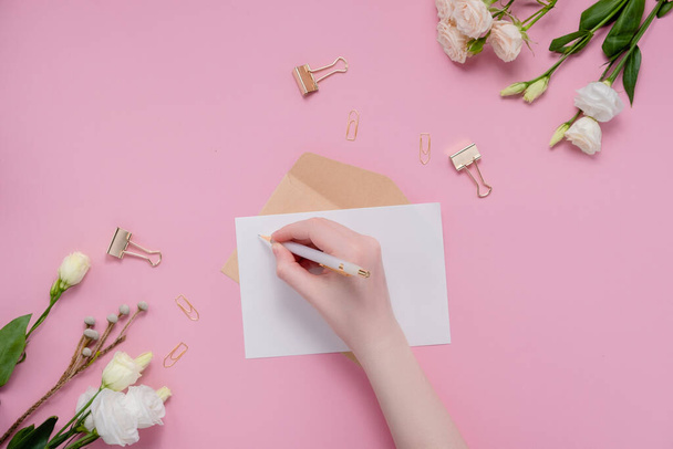 Vrouwelijke handen schrijven verlanglijstje bovenste horizontale weergave copyspace. Om bloemen en briefpapier op te noemen. Bovenste horizontale weergave - Foto, afbeelding