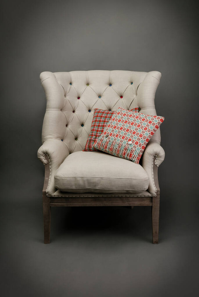 Крісло і 2 барвисті подушки на сірому фоні
 - Фото, зображення