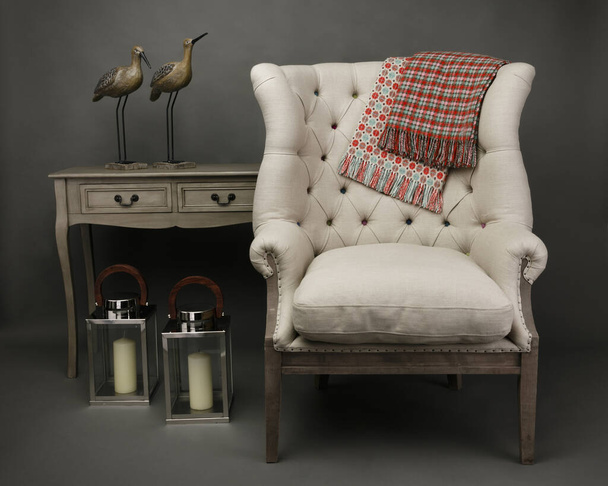 Armchair and 2 throws with side table with ornaments on grey background - Photo, Image