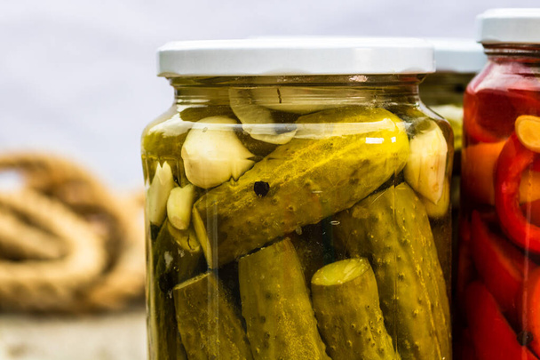 Close up of glass jar with pickles isolated. Preserved food concept, canned vegetables isolated in a rustic composition. - Photo, Image