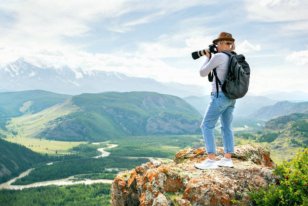Woman photographer taking photo at mountain peak. Hiker in the mountains. - Foto, afbeelding