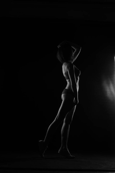 силуэт красивой женщины с коротким слухом в нижнем белье позирует на темном фоне студии     - Фото, изображение