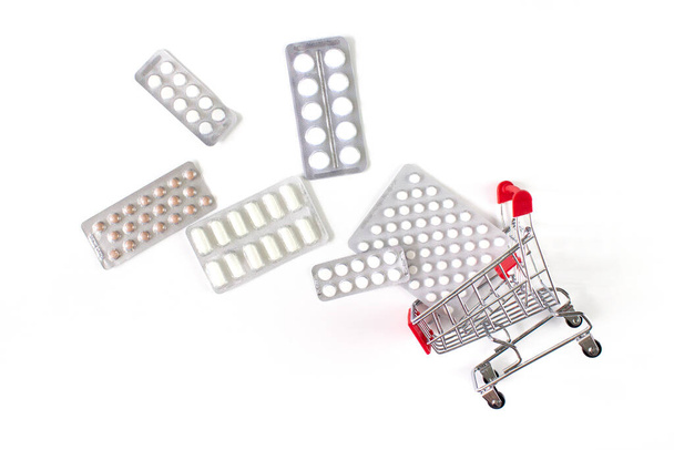 Blister pack tablets fall out out shopping cart isolated on white background. Online shopping and medicine delivery concept. Capsules, tablets in basket. Health care, pharmacy shipping. Stock photo. - Photo, Image