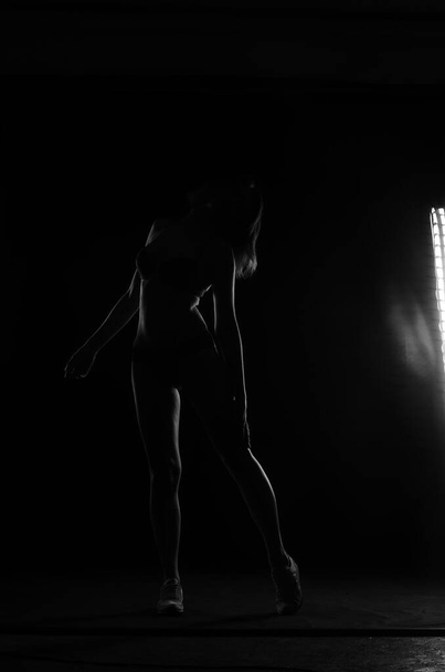 silhouette of beautiful woman with short hear in lingerie posing on dark studio background     - 写真・画像