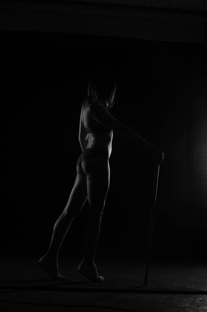σιλουέτα της όμορφης γυναίκας με σύντομη ακούσει σε εσώρουχα ποζάρουν σε σκούρο φόντο στούντιο     - Φωτογραφία, εικόνα