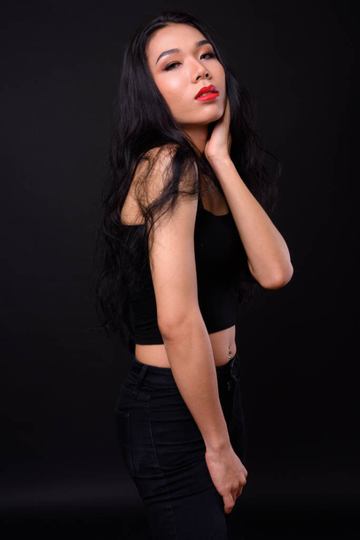 Studio shot of young beautiful Asian transgender woman against black background - Фото, зображення
