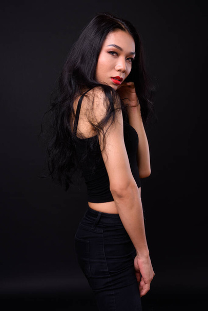 Studio shot of young beautiful Asian transgender woman against black background - Фото, изображение