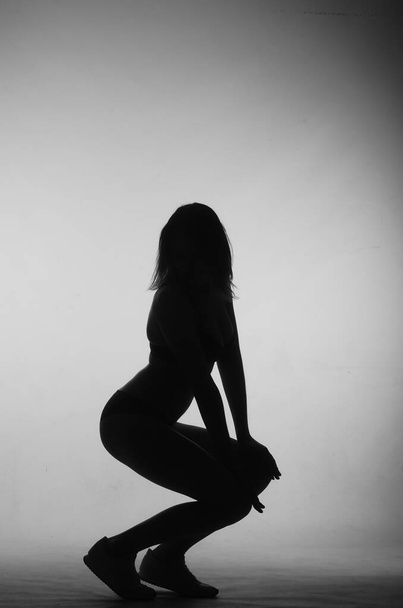 silhouette of beautiful woman with short hear in lingerie posing on light studio background     - Фото, зображення