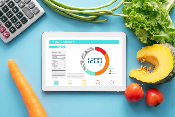 Calories counting , diet , food control and weight loss concept. tablet with Calorie counter application on screen at dining table with fresh vegetable and calculator. healthy eating lifestyle - Φωτογραφία, εικόνα