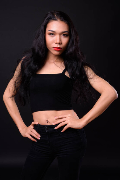 Студийный снимок молодой красивой азиатской трансгендерной женщины на черном фоне - Фото, изображение