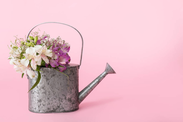 Watering can with flowers on color background - Fotó, kép