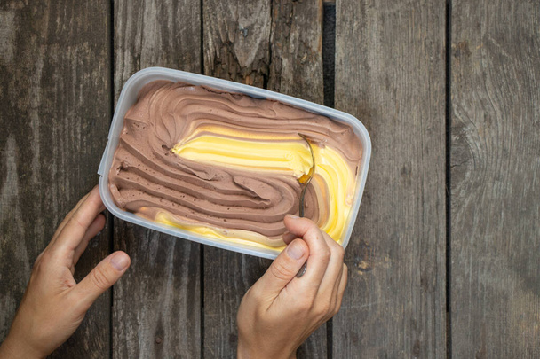 boîte avec crème glacée au chocolat orange et la main d'une femme sur une table - Photo, image