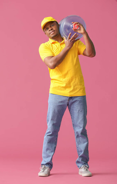 African-American delivery man with bottle of water on color background - Foto, Imagem