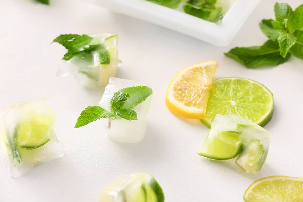 Ice with frozen citrus fruits on white background - Photo, image