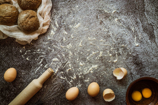 összetevők sütés kenyér, tojás, sodrófa, keverő hazugság egy szürke asztalon - Fotó, kép