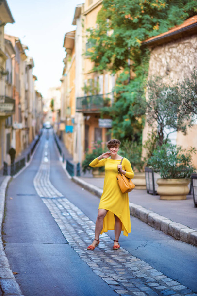 Vertical picture of old narrow stone street of Aix-en-Provence, France with tourist woman in yellow dress with yellow bag. Travel tourism destination Provence. - Fotó, kép
