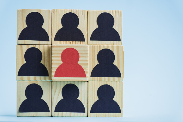 vierkant van houten blokken met zwarte en rode menselijke pictogrammen op blauwe achtergrond, leiderschap concept  - Foto, afbeelding
