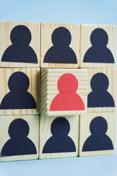 négyzet alakú fa blokkok fekete és piros emberi ikonok kék háttér, vezetői koncepció - Fotó, kép