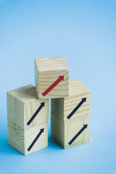 blocs de bois avec des flèches noires et rouges sur fond bleu, concept de leadership  - Photo, image