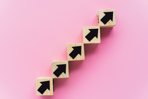 top view of wooden blocks with black arrows on pink background, business concept  - Fotoğraf, Görsel