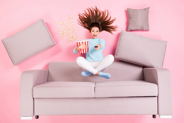 Top view above high angle flat lay flatlay lie concept of her she nice attractive cheerful glad girl sitting on divan lotus pose switching channel eating snack isolated on pink pastel color background - Foto, afbeelding