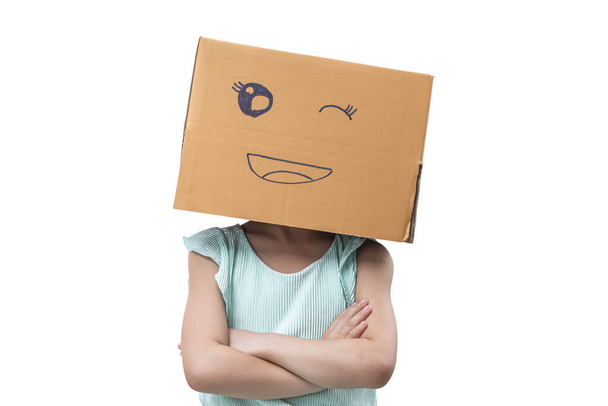 Little girl wearing cardboard box on his head with smiley face, Isolated on white background. - Foto, afbeelding