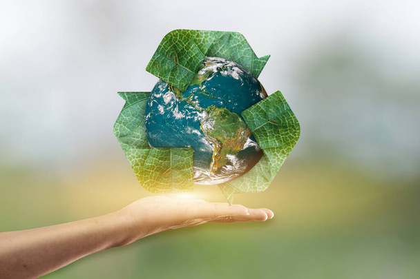 Ręczne trzymanie planety ziemi i recyklingu ikony na rozmazane zielone tło. Elementy tego obrazu są dostarczane przez NASA - Zdjęcie, obraz