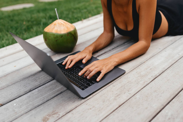Freiberuflerin tippt auf Laptop mit frischer Kokosnuss . - Foto, Bild