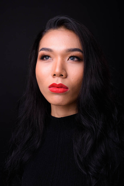 Siyah arka plana karşı genç ve güzel Asyalı transseksüel iş kadınının stüdyo çekimi. - Fotoğraf, Görsel