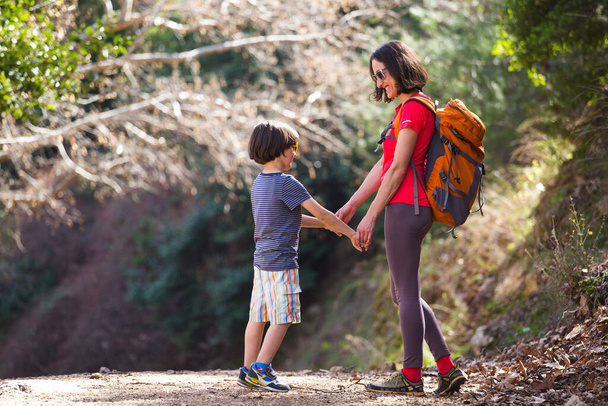 Bir kadın oğluyla ormanda yürür, annesiyle yürüyüşe çıkar, sırt çantalı bir çocuk parka gider, çocuklarla seyahat eder, çocuk annesinin elini tutar, dağ yolu, Anneler Günü.. - Fotoğraf, Görsel