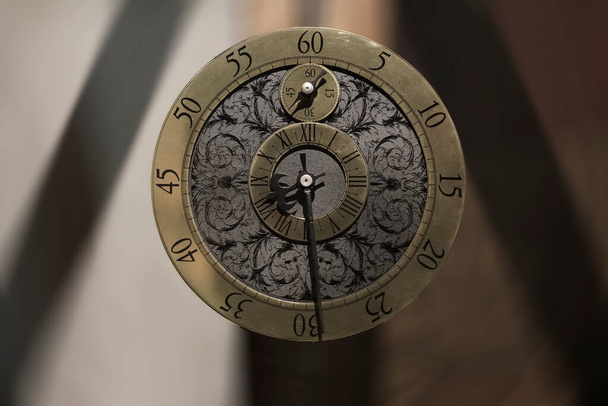 Antique old clock. Watch clock mechanism unusual abstract texture round pattern background. Golden old fashion clock dial with roman and arabic numerals. Clock hands pointers - Φωτογραφία, εικόνα