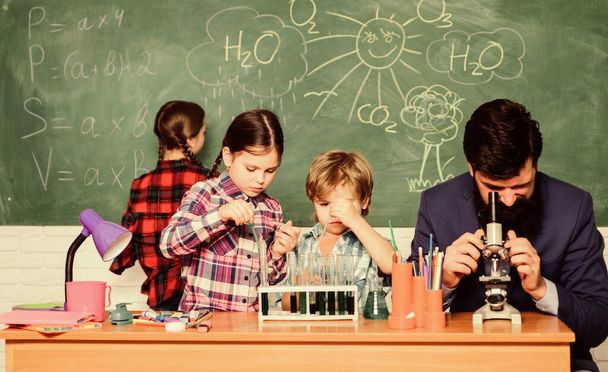 Fascinating chemistry lesson. Man bearded teacher and pupils with test tubes in classroom. Observe reaction. Science is always the solution. School chemistry experiment. Explaining chemistry to kids - Фото, зображення