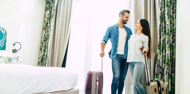 Young beautiful happy excited couple in love with suitcases in a modern hotel during vacation - Foto, Imagem