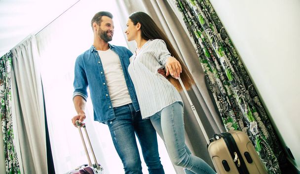 Young beautiful happy excited couple in love with suitcases in a modern hotel during vacation - Photo, Image