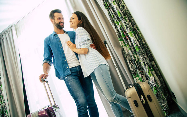 Young beautiful happy excited couple in love with suitcases in a modern hotel during vacation - Foto, imagen
