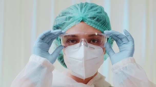 Woman medical worker with protective face mask KN95 takes off medical glasses - Imágenes, Vídeo