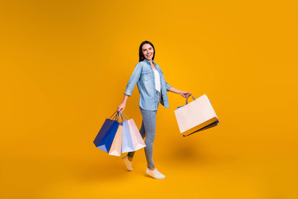 Full length body size view of nice attractive pretty glad cheerful girl going carrying new things dress clothes bargain boutique trend isolated on bright vivid shine vibrant yellow color background - Foto, Imagen