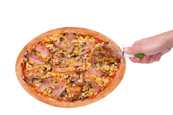Séf kézzel vágja a finom pizza csirkemell, kukorica, szalonna és gomba, egy pizza vágó, elszigetelt fehér háttér, szög nézet - Fotó, kép