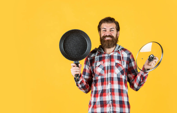 bearded man hold kitchen pan. brutal hipster cooking with saucepan. housekeep husband cook in pot. mature chef in checkered shirt. prepare meal food at home. professional cook - Foto, Bild