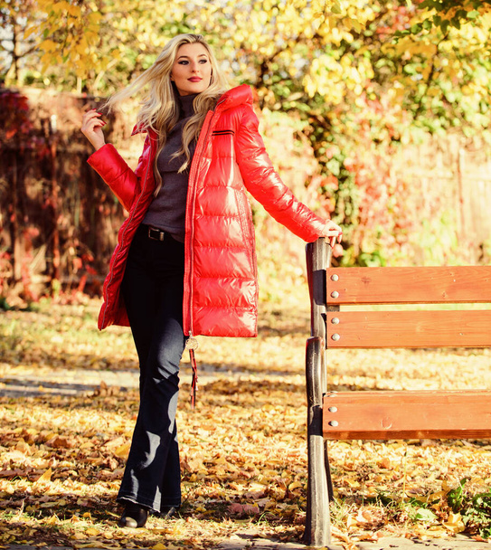 Lady attractive fashionista posing in jacket. Jacket for fall season concept. Woman fashionable blonde with makeup stand in autumnal park. Girl wear red bright warm jacket. Fall fashion concept - Photo, image