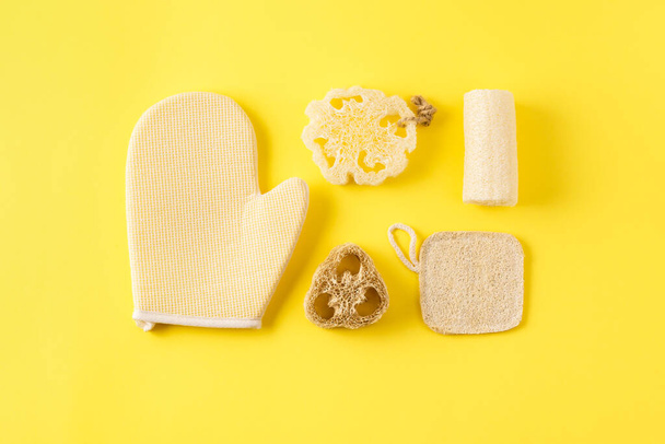 Different kinds of sponges on yellow surface. Reusable skin care tools for bath from ecological loofah luffa and bamboo material. Zero waste bathroom accessories. - Фото, зображення