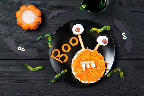 Vicces pirítós répa alakú szörny és gumi cukorka férgek, szendvics gyerekeknek Halloween ötlet, felső nézet fa háttér - Fotó, kép