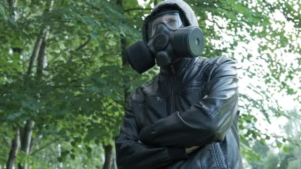 Ένας άντρας με μάσκα αερίου στο καπό στο δάσος. προστασία από τα χημικά όπλα, επιδημία ιού - Πλάνα, βίντεο