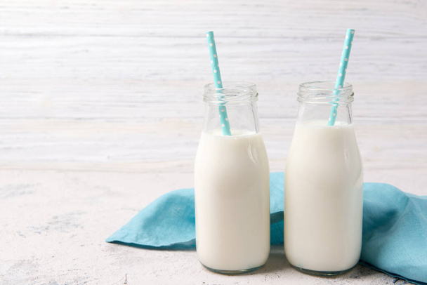 Two bottles of milk with blue straws on wooden background - Photo, Image