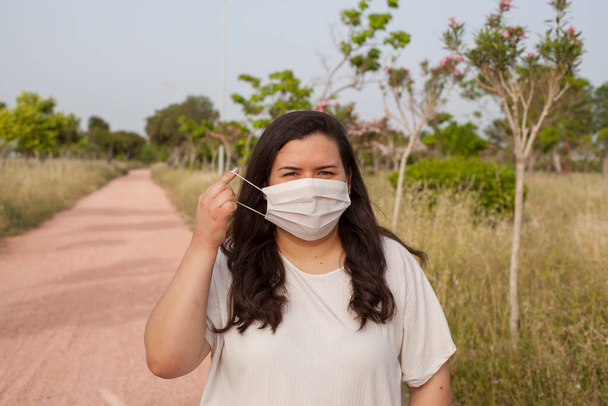 Lady protected by a mask outdoors to protect from Covid-19. Natural funds, trees and fresh air. - Фото, изображение