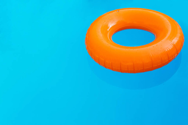 Una rosquilla naranja flotando en la piscina
. - Foto, imagen